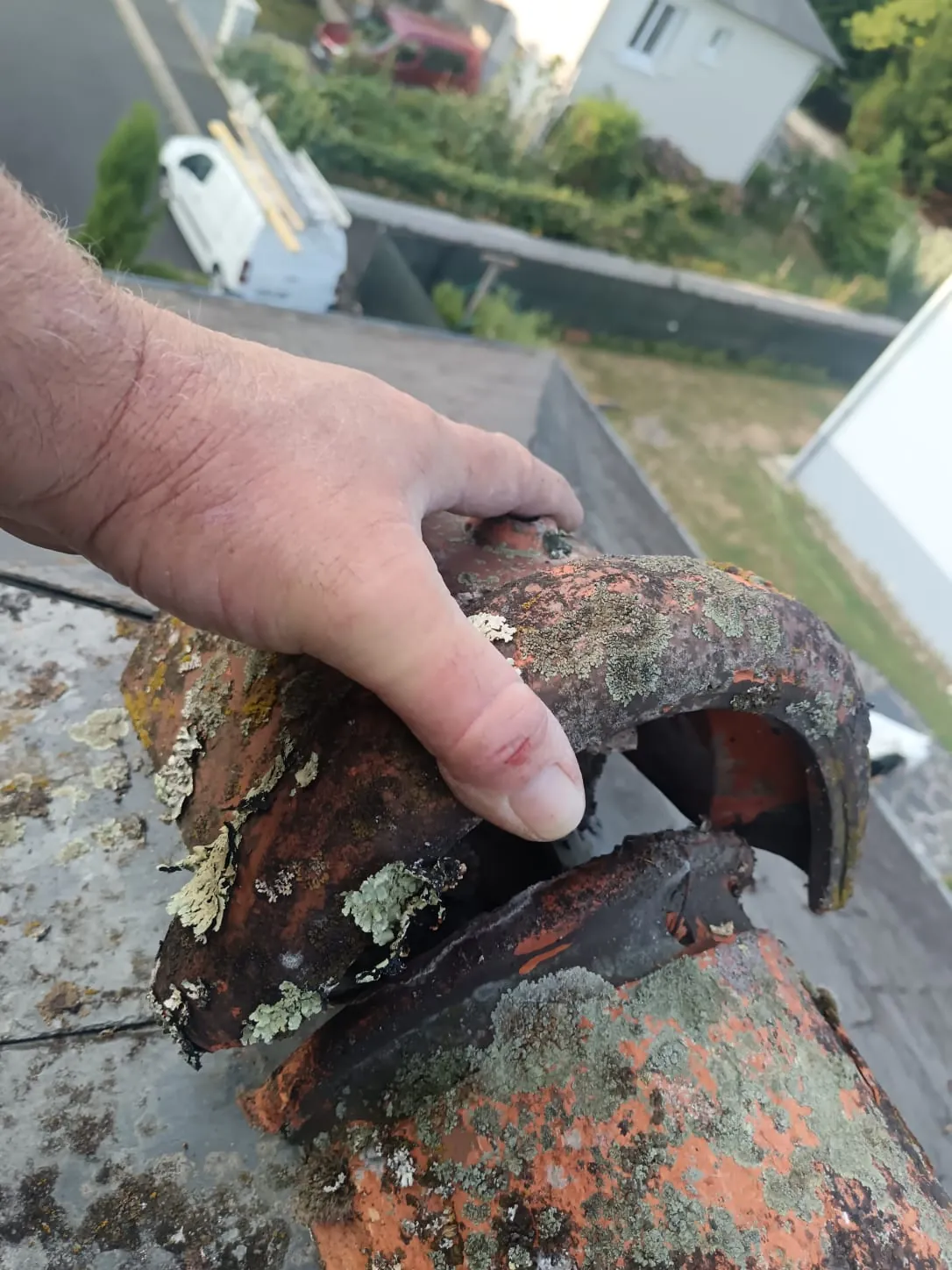 Faîtière fendue couverte de lichens, tenue en main lors du contrôle sur le toit