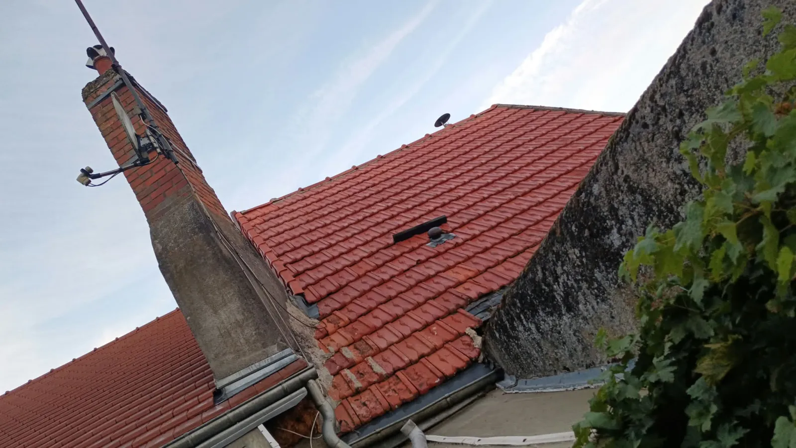 Toiture en tuiles mécaniques rouges à Tours, cheminée en briques avec abergement en zinc, bande de solin le long du mur voisin et descente d'eau pluviale